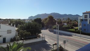 A residential street with houses, a clear sky, and mountains in the background.