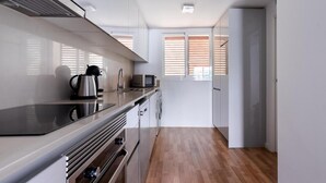 A modern kitchen with white cabinets, a stainless steel stove, and a wooden floor. - Salamandra Altea 17 By Vero (Altea)