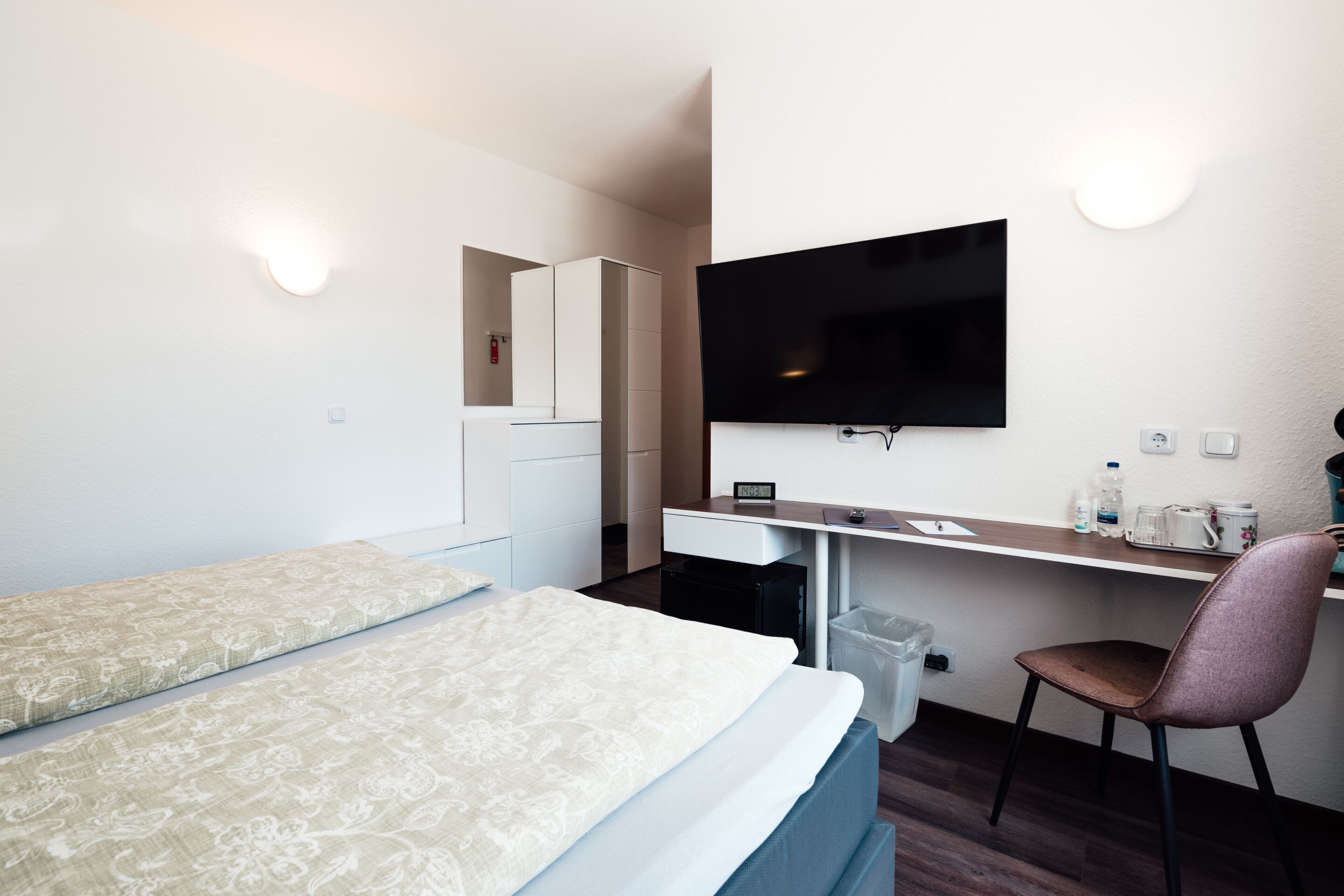 Habitación de hotel con dos camas, un escritorio con computadora, televisión y una silla.