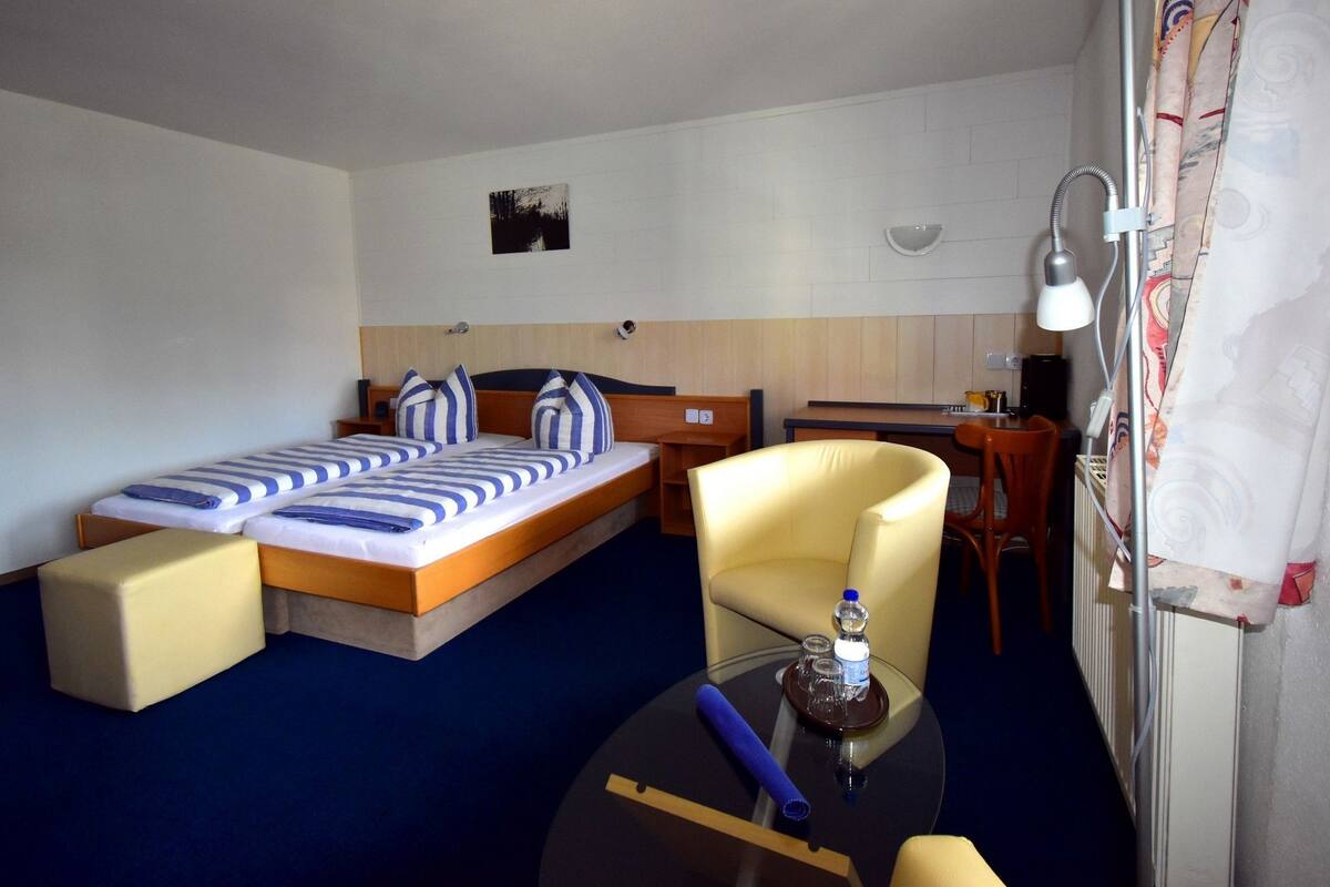 Ett hotellrum med en säng, en stol, ett litet bord och ett skrivbord.