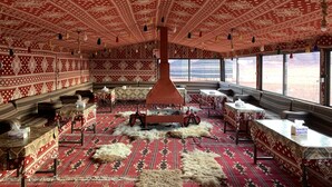 A room with patterned red and white walls, a central red column, and a large window offering a desert view. - Desert Bird Camp (Wadi Rum)