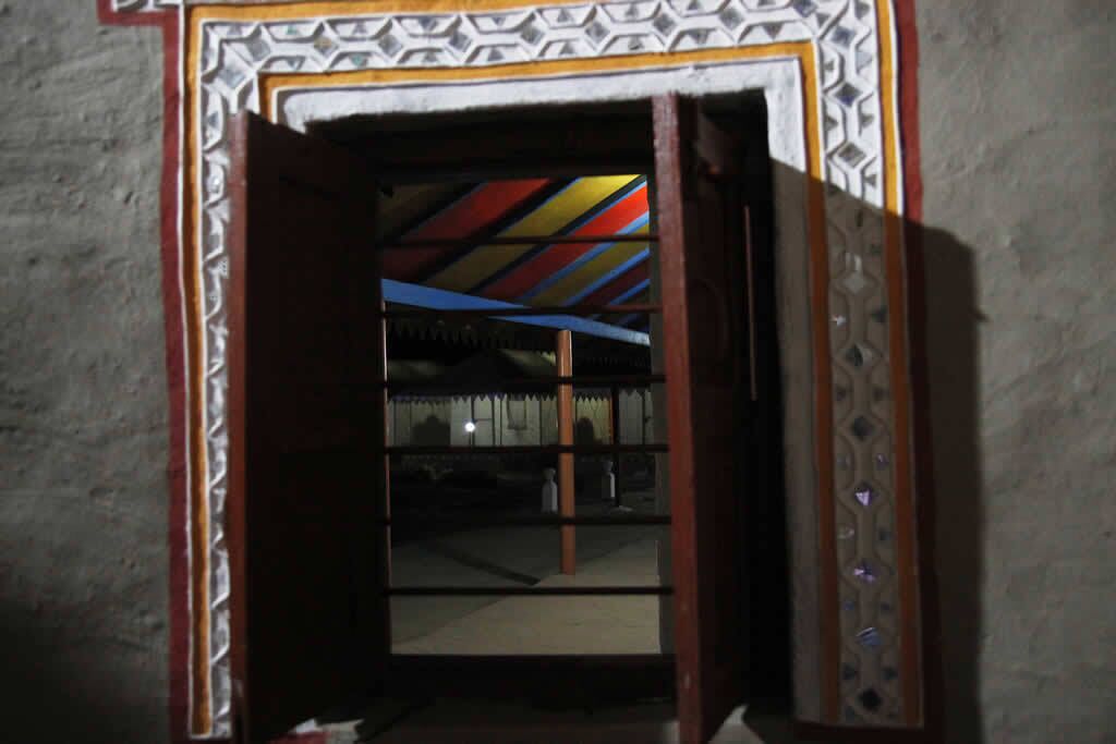 An open doorway with a patterned frame and a view of a room with a striped ceiling.