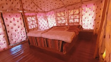 Una habitación con cama, una mesita y cortinas de estampado floral.
