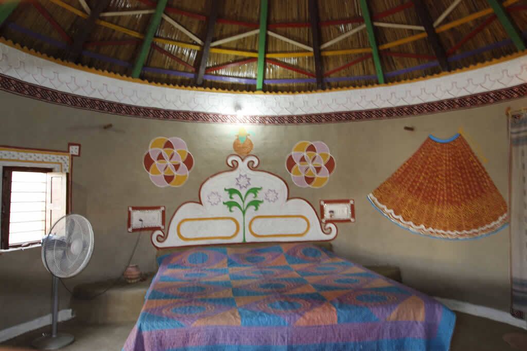 A room with a bed, a fan, and a decorative wall.