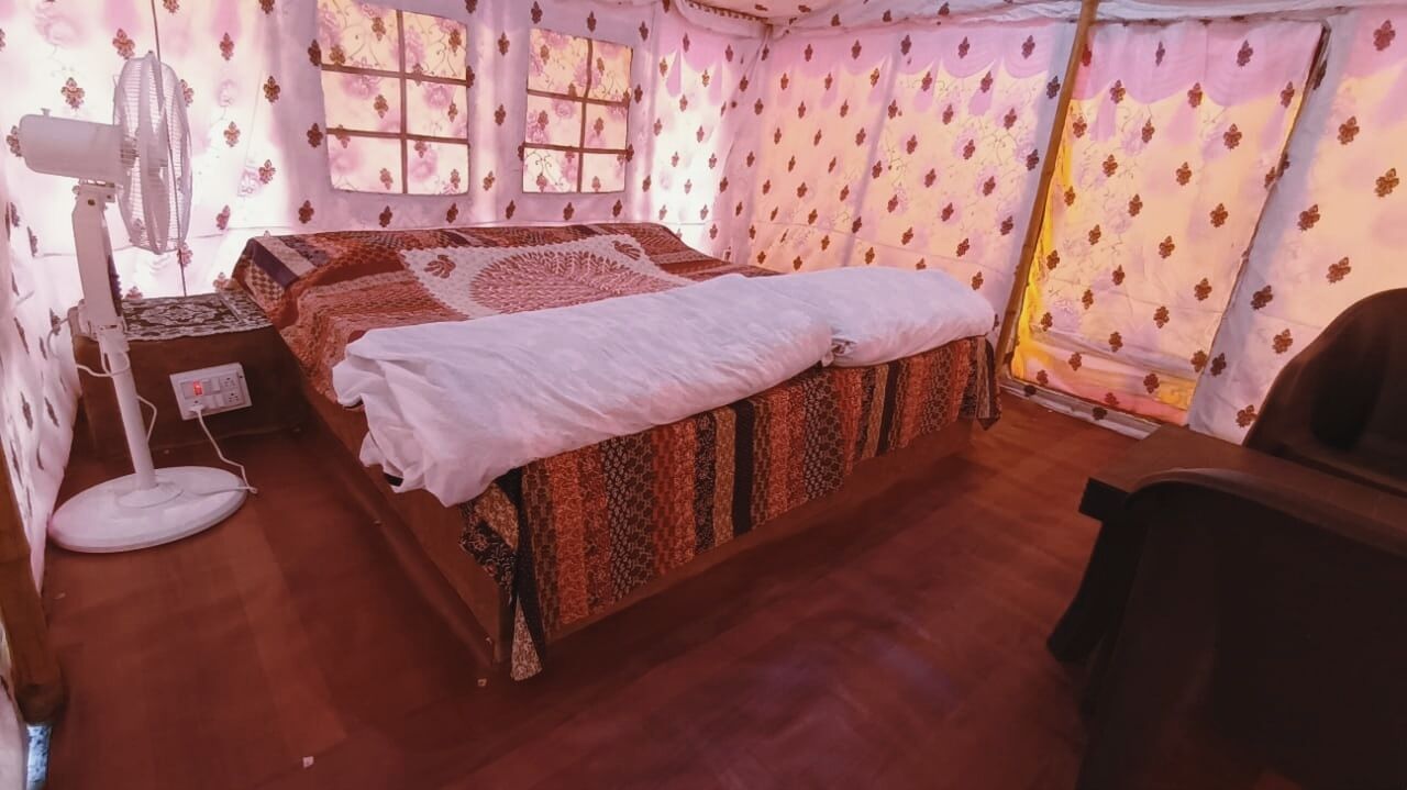 A room with a bed, a fan, and a window with curtains.