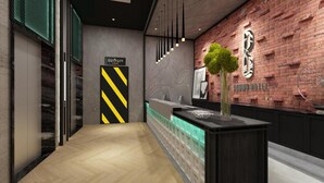 Un lobby moderno de hotel con una recepción, un cartel del Hotel Brown y un árbol decorativo.