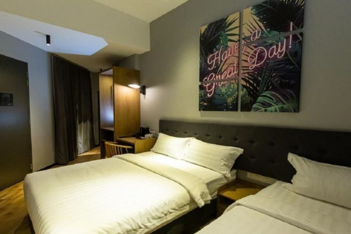 A hotel room with a large bed, a desk, and a wall-mounted artwork that says "Have a great day!"