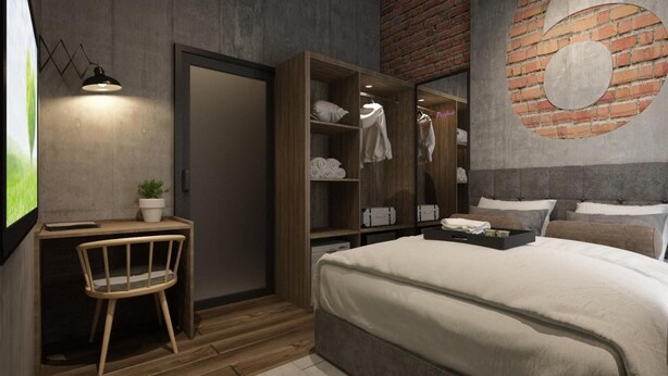 Un dormitorio moderno con un escritorio de madera, una silla y un armario, una cama con ropa blanca y una pared de ladrillo con un diseño circular.