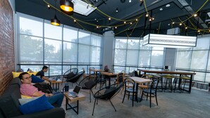 Un espacio de coworking moderno con ventanas amplias, sillas negras y mesas con portátiles.