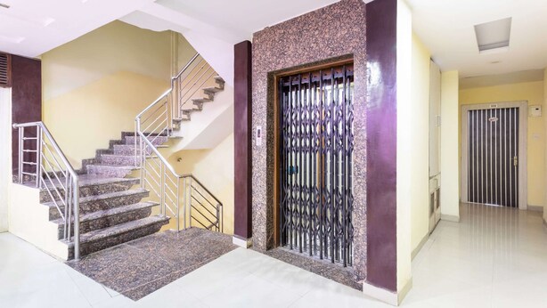 Un pasillo limpio y bien iluminado con una escalera de mármol, una reja metálica decorativa y una puerta con el número 108.