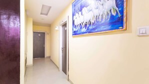 Un pasillo con un cuadro de caballos blancos en la pared, una puerta con reja de metal y un interruptor de luz en la pared.