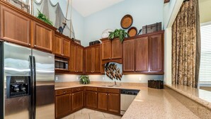 A modern kitchen with wooden cabinets, stainless steel appliances, and a granite countertop. - ✦Best Deal✦Cozy Home w/ WiFi, Baby Gear, 6mi to Disney, Onsite Theatre/Pool✦ (Kissimmee)