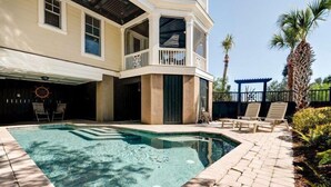 Une piscine à l’eau d’un bleu cristallin, entourée d’une terrasse en briques et de chaises longues.