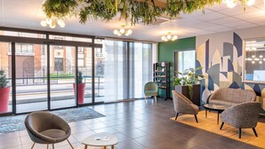 Un interior moderno con una zona de estar, ventanas amplias y una estantería.