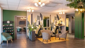 Un lobby moderno con una pared verde, un mostrador de recepción y una zona de estar.