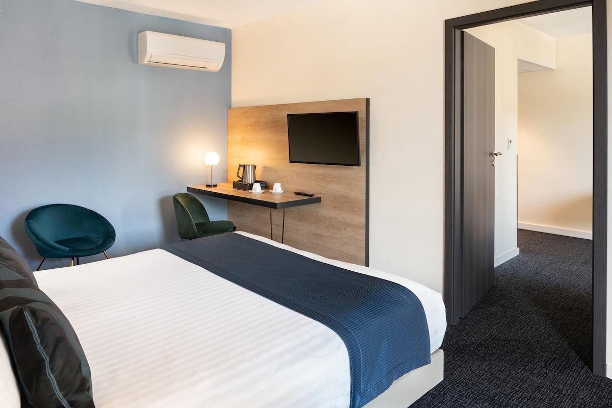 Une chambre d’hôtel équipée d’un lit, d’un bureau avec un téléviseur à écran plat, d’une chaise et d’un appareil de climatisation.