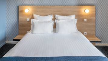 A neatly made bed with white linens and a blue accent at the foot.