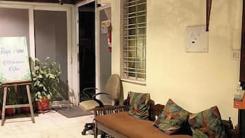 A room with a sofa, a small table, a potted plant, and a sign that reads 'Royal Palms Welcome.'