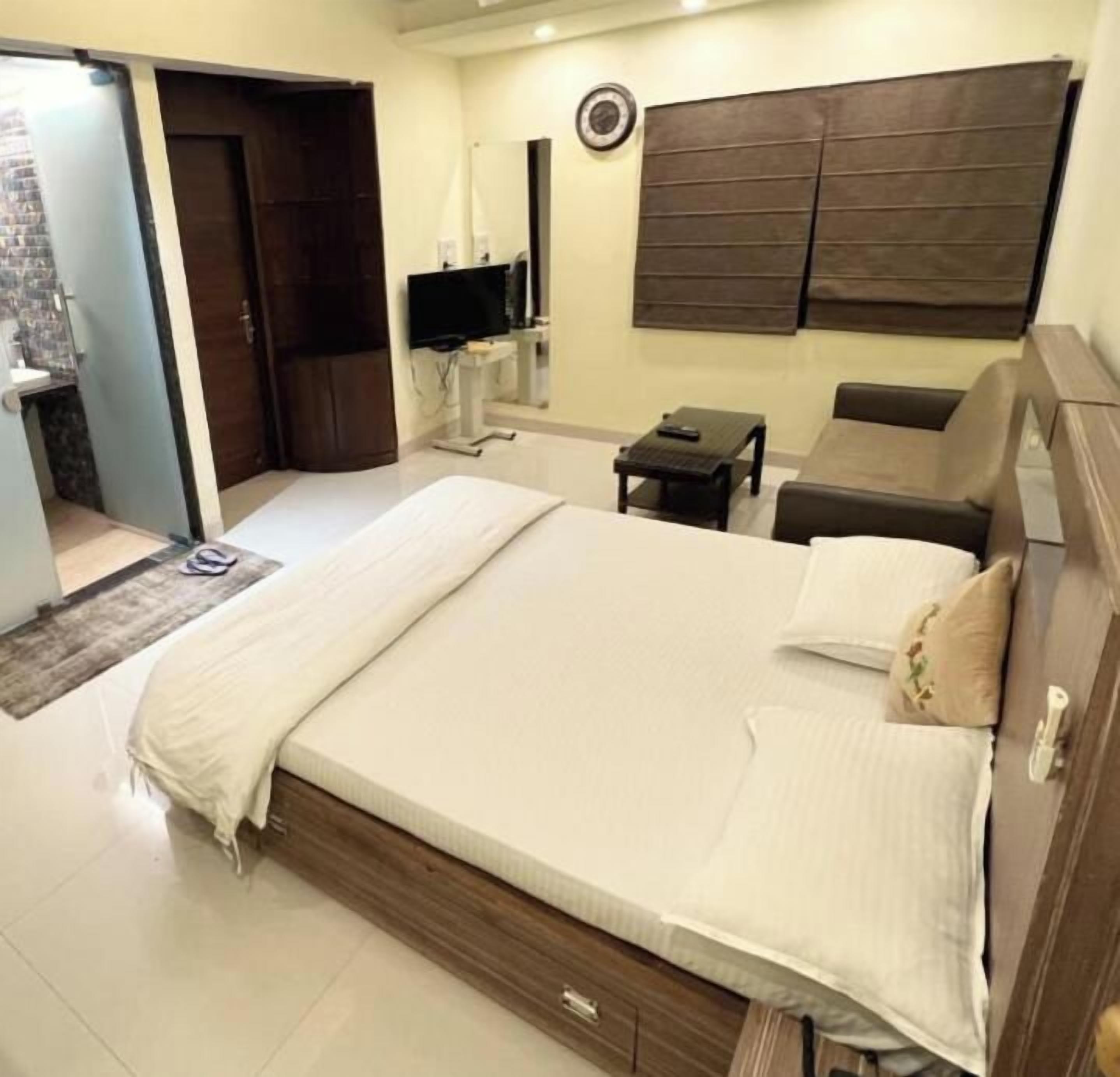 A hotel room with a bed, a TV, a sofa, and a desk.