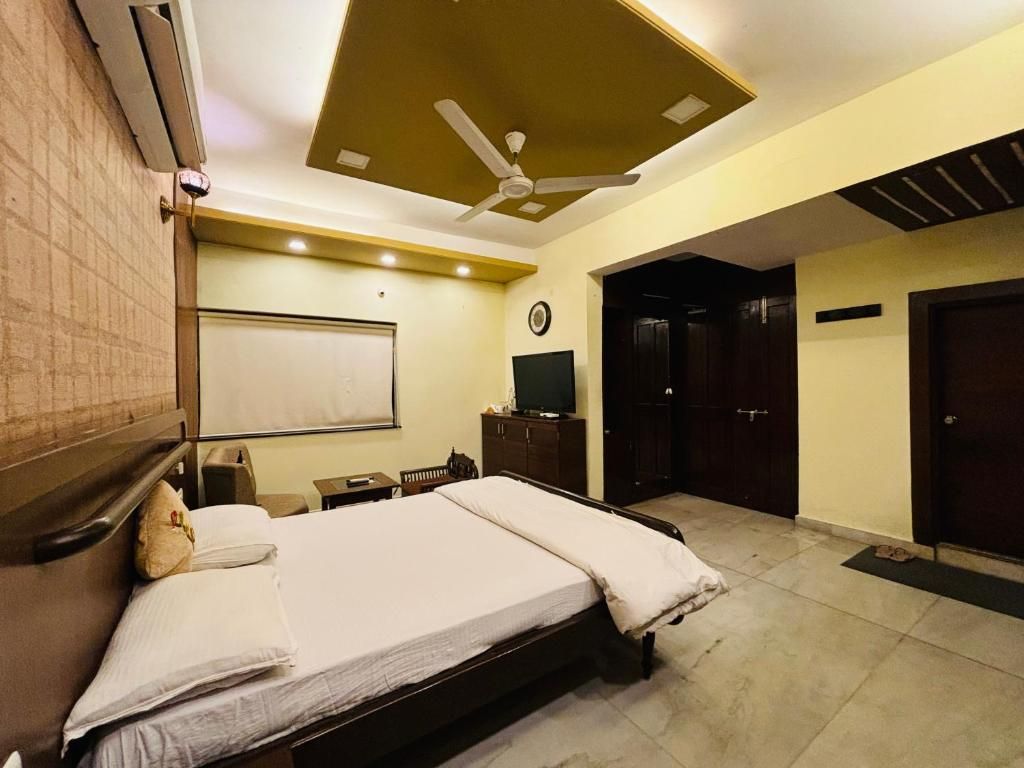 A hotel room with a bed, a desk, a chair, a ceiling fan, and a wardrobe.