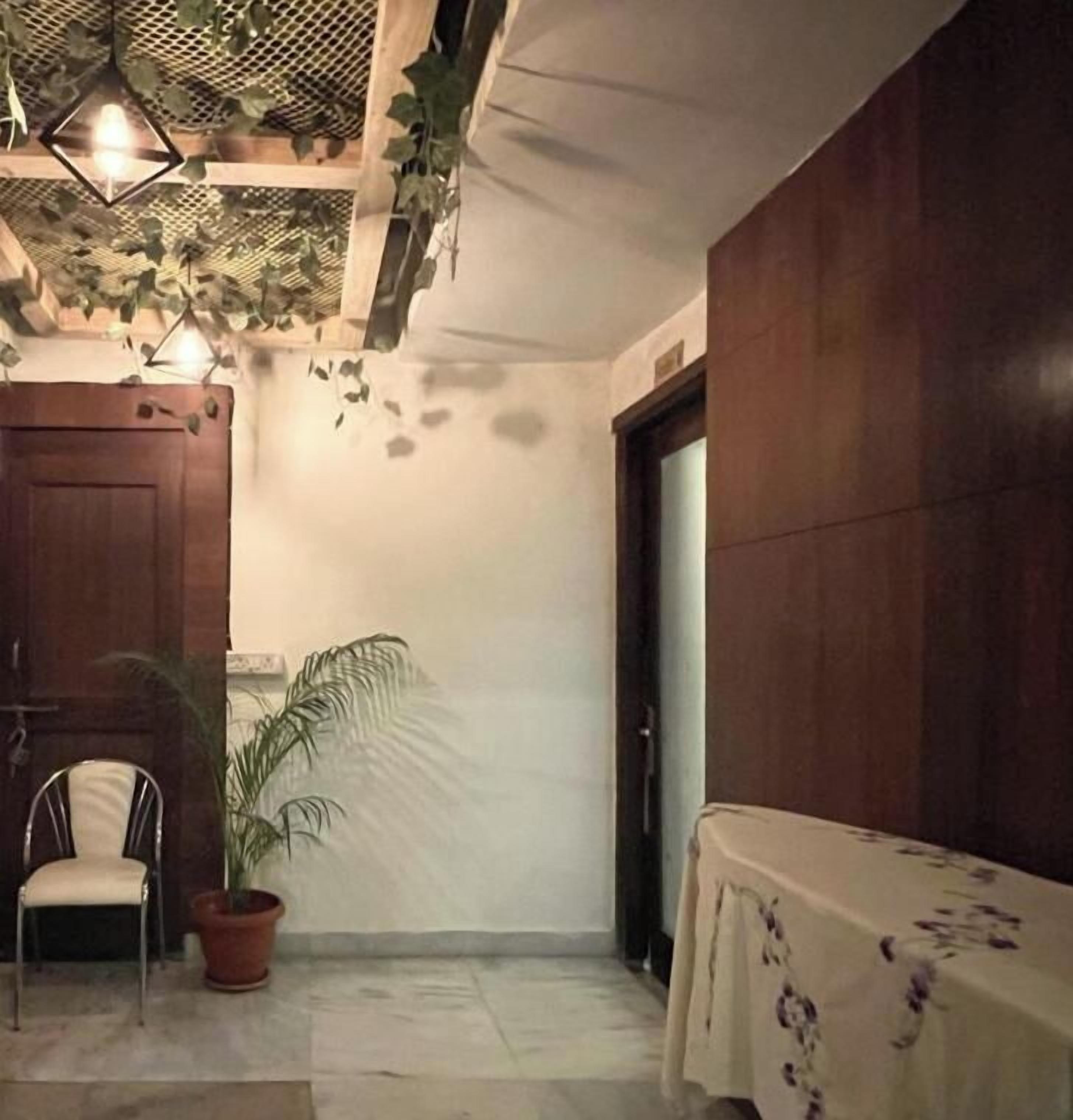 Una habitación con puerta de madera, una silla, una planta en maceta y una mesa con mantel.