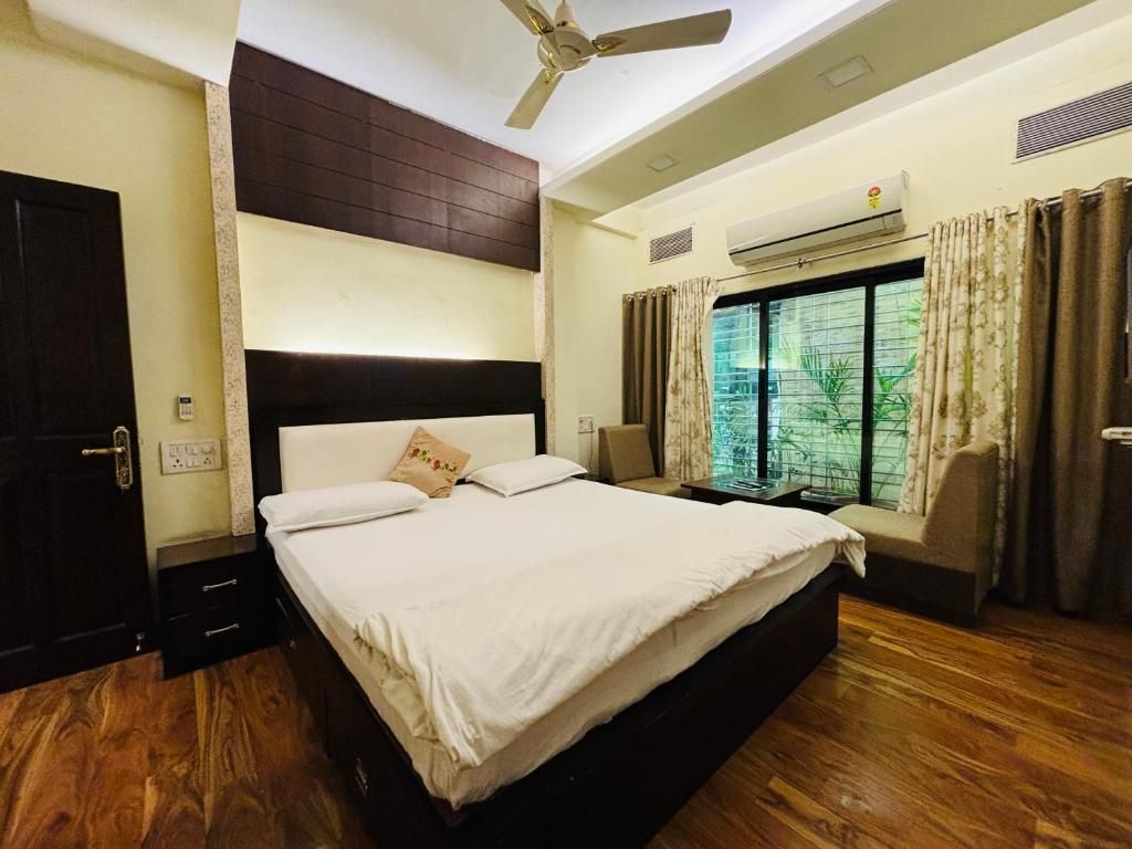 A bedroom with a bed, a ceiling fan, an air conditioning unit, and a window with curtains.
