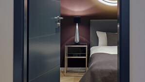A modern hotel room with a bed, a bedside table, a lamp, and a circular light fixture on the wall. - Patentkrug Design Hotel (Oldenburg)