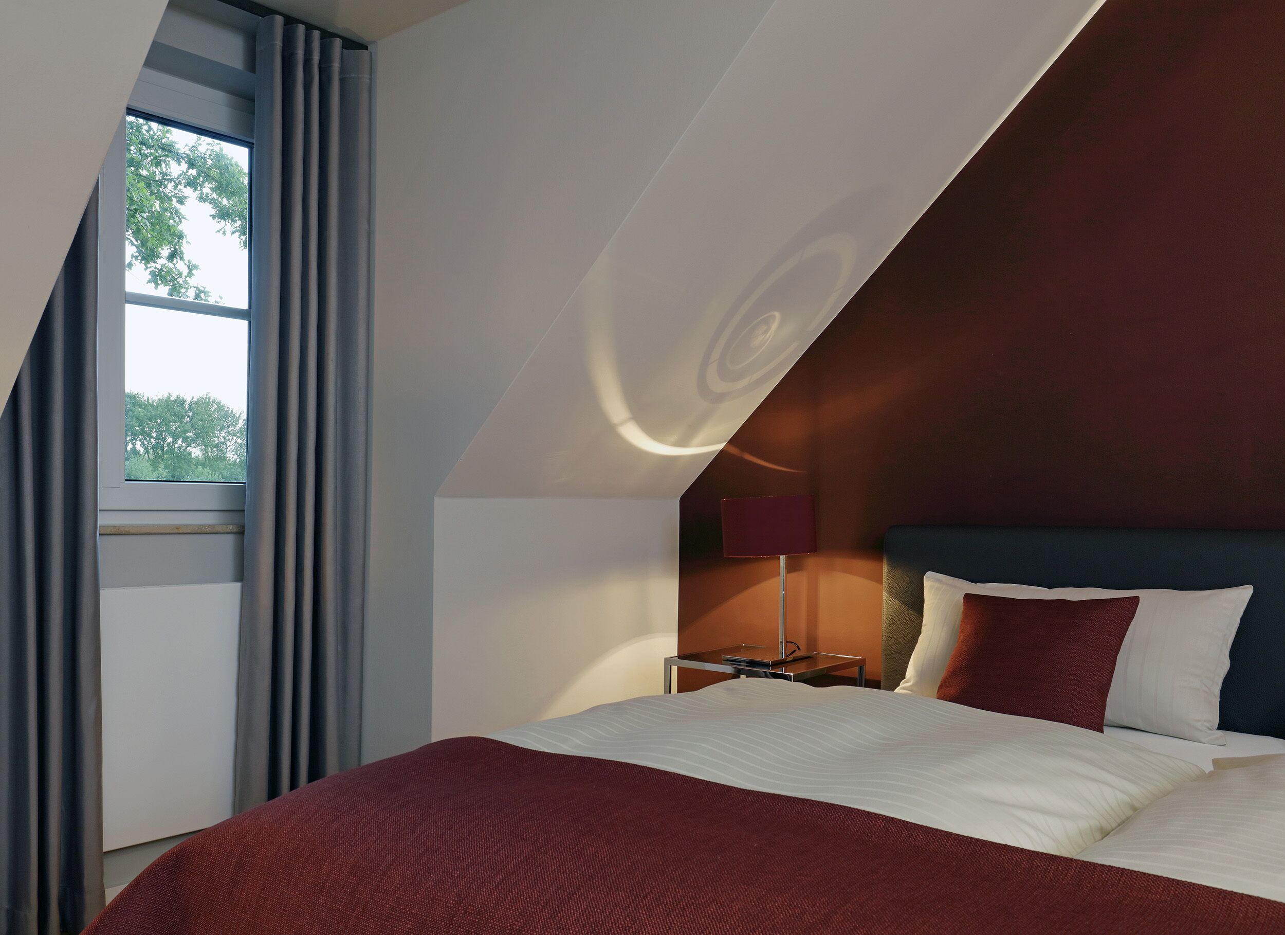 Una habitación de hotel moderna con una cama grande, un escritorio y una ventana con cortinas.