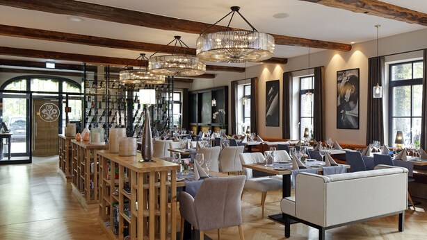 A spacious restaurant with wooden floors, high ceilings, and large windows. - Patentkrug Design Hotel (Oldenburg)