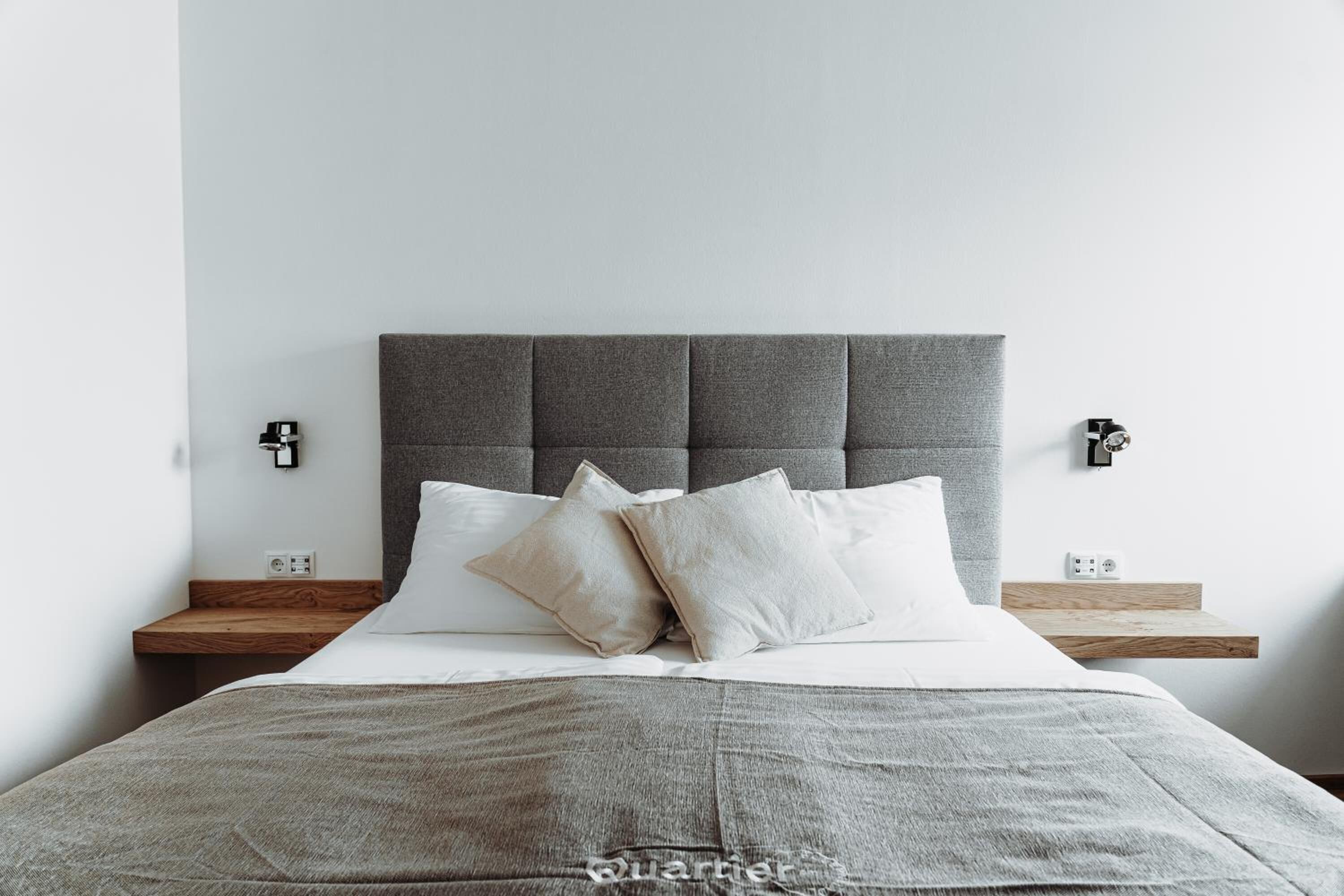 A modern bedroom with a tufted headboard, a neutral color palette, and a minimalist design.