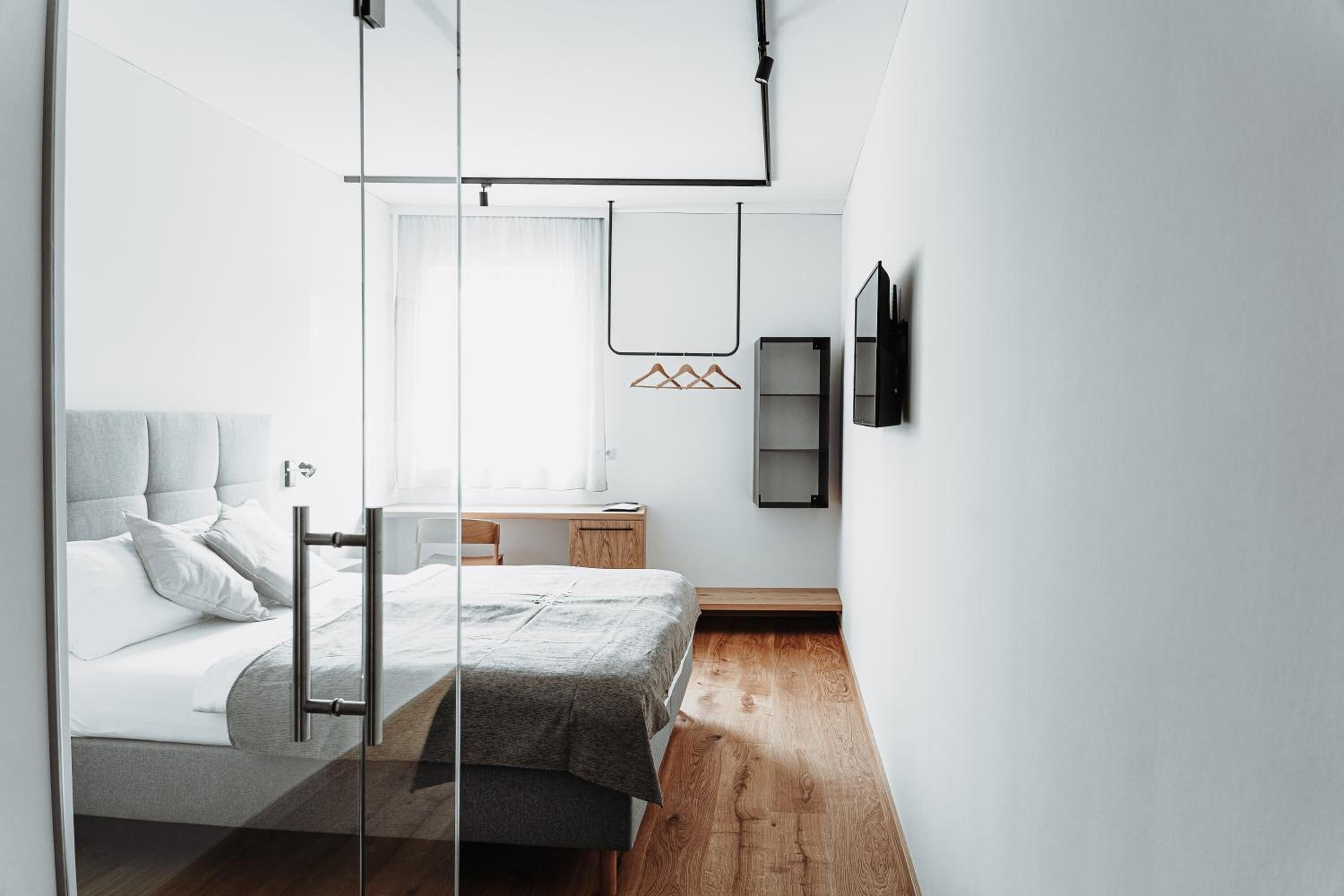 Ein modernes Schlafzimmer mit Bett, Nachttisch und einem Fenster mit Vorhängen.