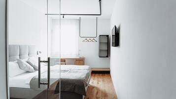 Un dormitorio moderno con cama, mesita de noche y ventana con cortinas.