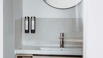 A bathroom with a round mirror, a sink, and two toiletry bottles.