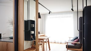 Uma sala de estar moderna com uma mesa de jantar de madeira, um sofá e um rack de entretenimento preto.