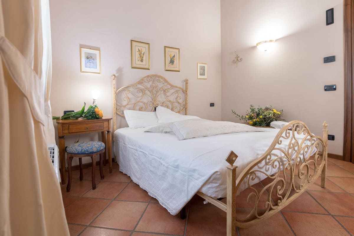 A bedroom with a bed, a desk, and a chair. There are framed pictures on the wall.