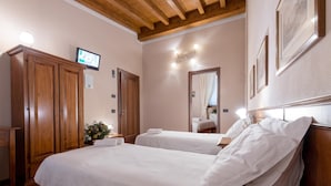 A bedroom with two beds, wooden wardrobe, a television, and a mirror. - Le Rondini (Bagnolo Mella)