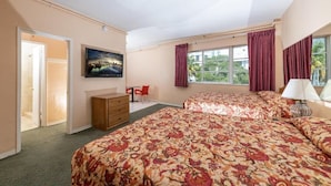 A hotel room with two beds, a desk, a chair, a TV, and a window with curtains.