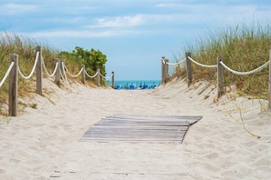 Een houten pad dat naar een strand leidt, met een touwbalk.