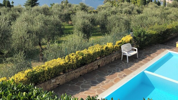 A poolside view with a clear view of the sea and mountains in the background. - Apartment Enchanting Lake View, convenient to the Center and the Beaches (Malcesine)