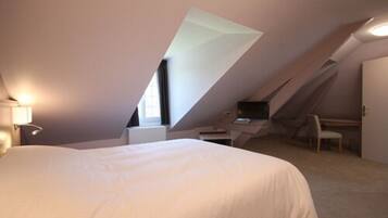 A bedroom with a large bed, a desk, and a chair.