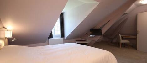 A bedroom with a large bed, a desk, and a chair.