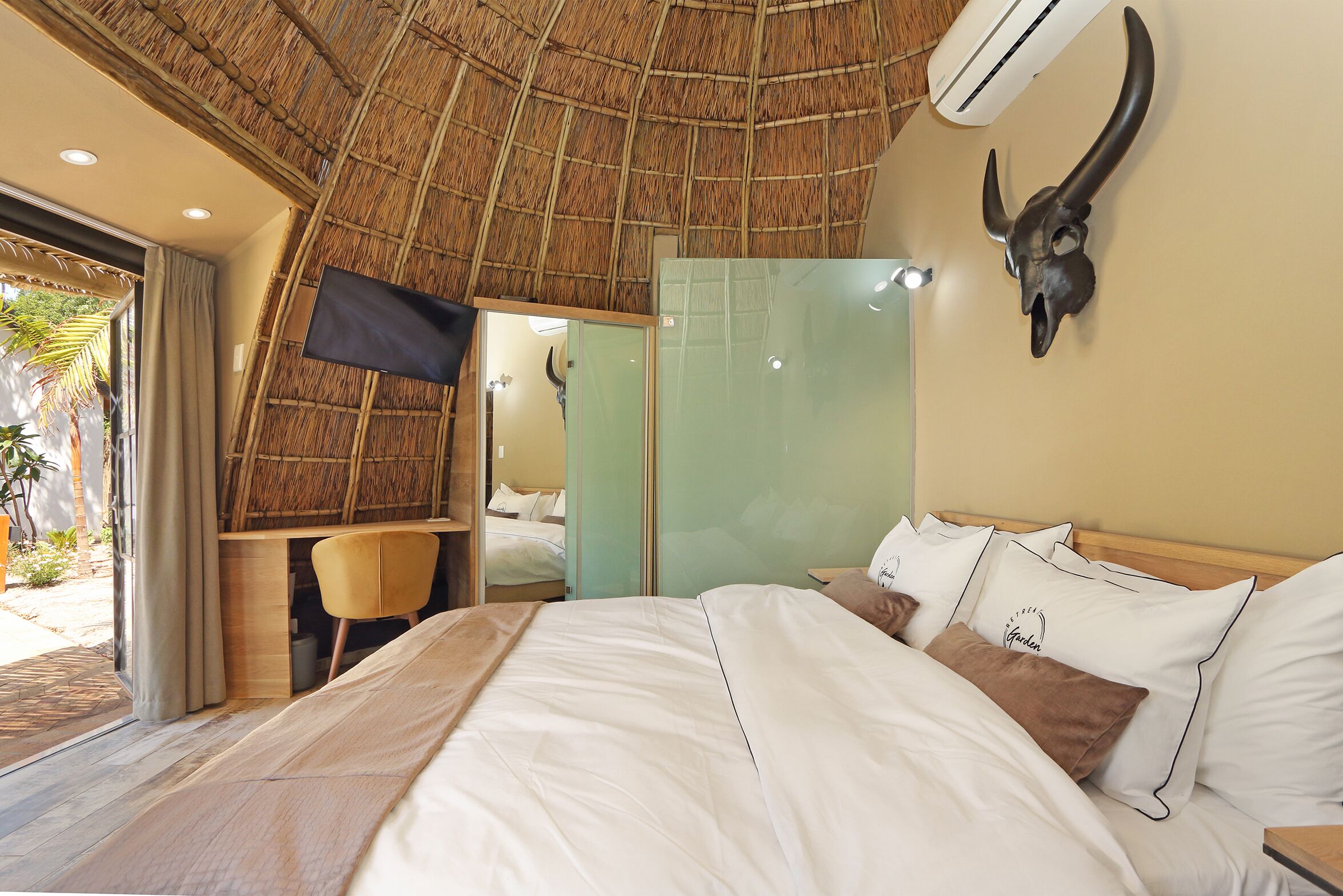 A bedroom with a bed, a desk, a chair, a TV, and a bull skull decoration.