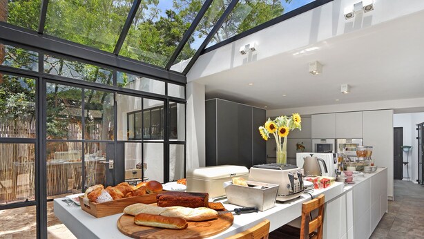 Una cocina moderna con una isla grande, muebles blancos y vistas amplias a través de ventanas.