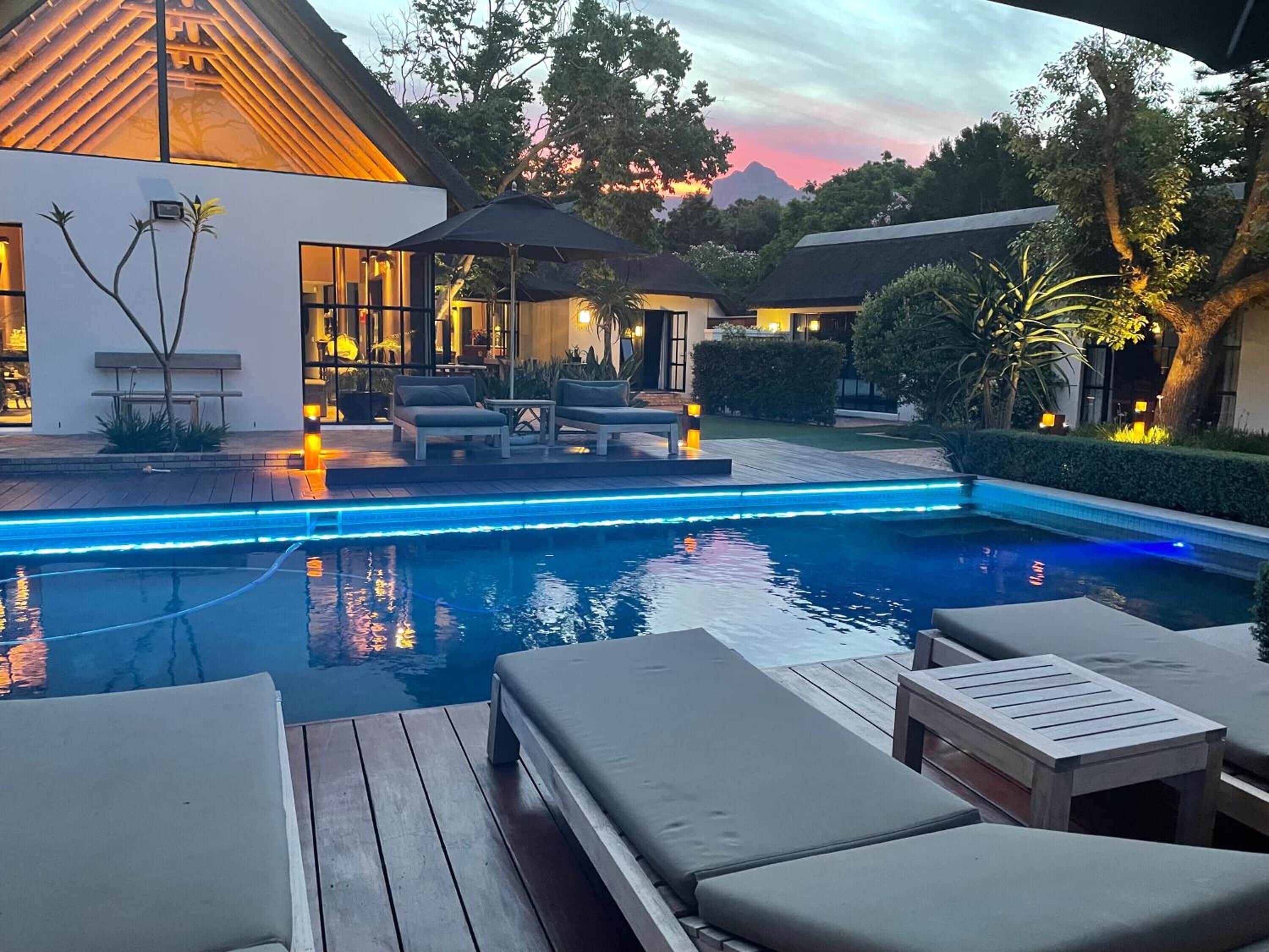 A modern outdoor pool area with lounge chairs and a wooden deck.