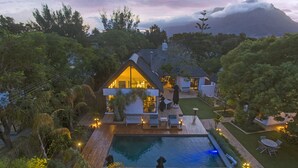 Una casa moderna con piscina, mobiliario de exterior y un jardín cuidado.