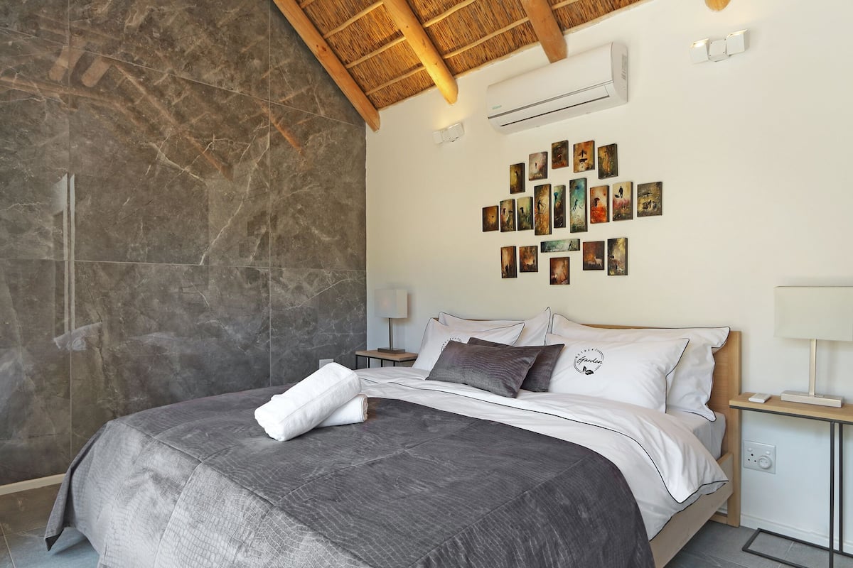 Een moderne slaapkamer met een groot bed, een stenen muur en een plafond met houten balken.