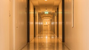 Ein langer, gut beleuchteter Hotelkorridor mit Türen an beiden Seiten zu den Zimmern.