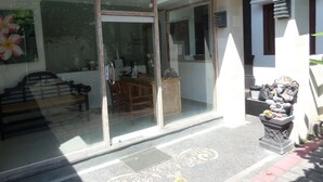 A building with a glass door entrance, a wooden bench outside, and a statue on the right.