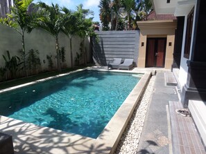 A rectangular swimming pool with clear water, surrounded by a low stone border. - Krisna Seminyak (Seminyak)