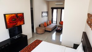 A modern hotel room with a large bed, a TV, a sofa, and a coffee table.